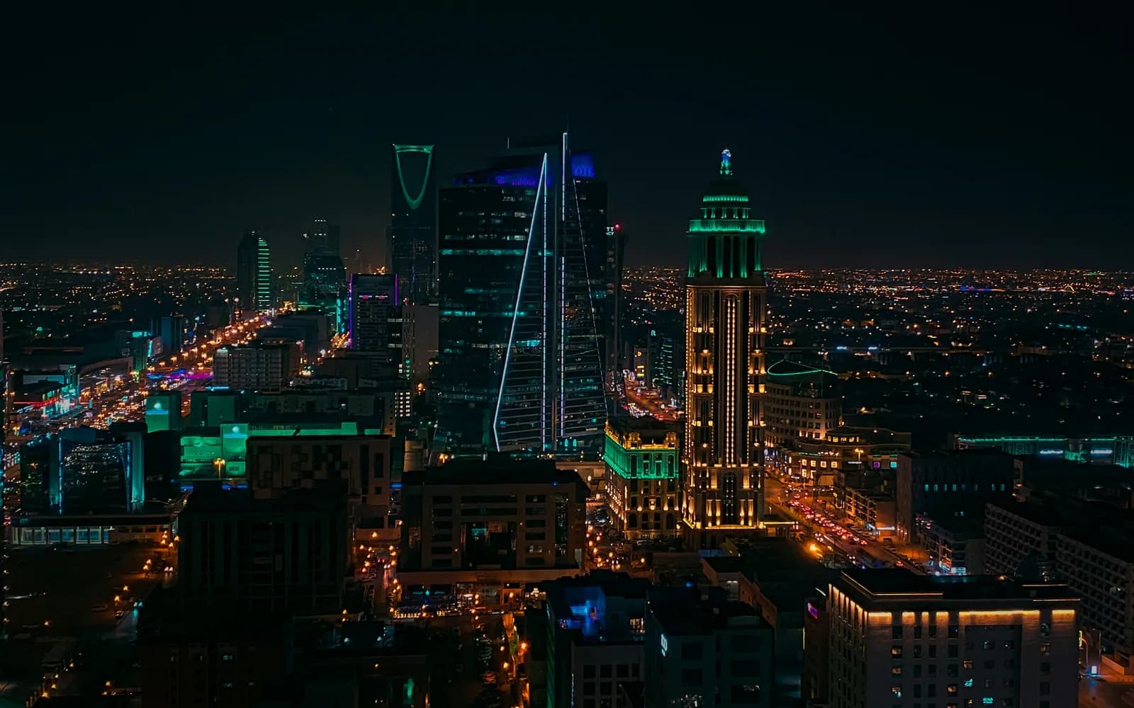 The Riyadh skyline at night, the Kingdom Centre lit green above the city lights