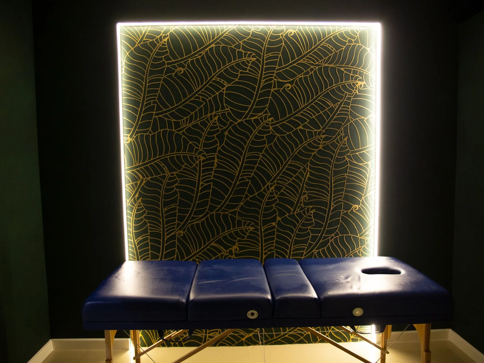 A treatment table in a dark room against a single lit gold panel