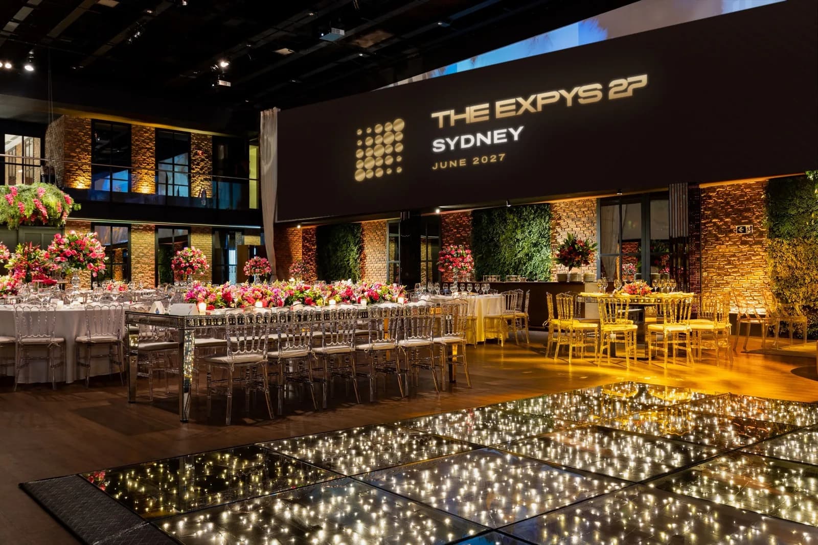 A dining room under a long projection band showing THE EXPYS 27 and Sydney
