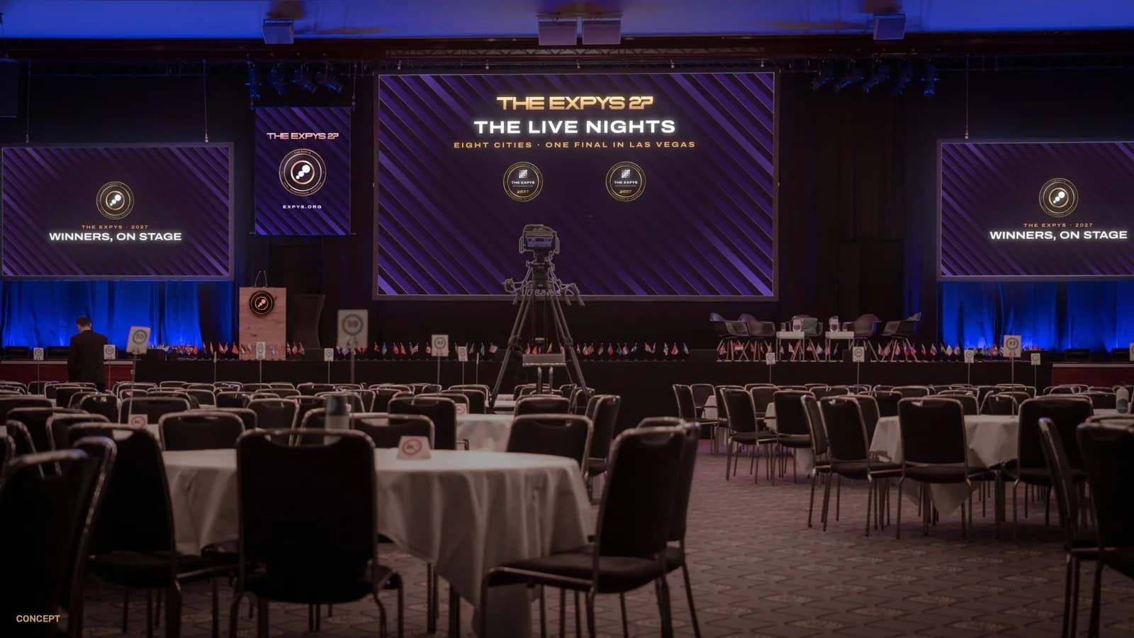 A ballroom set for dinner, with the Expys slides on the centre screen, the two side screens, the hanging banner and the lectern.