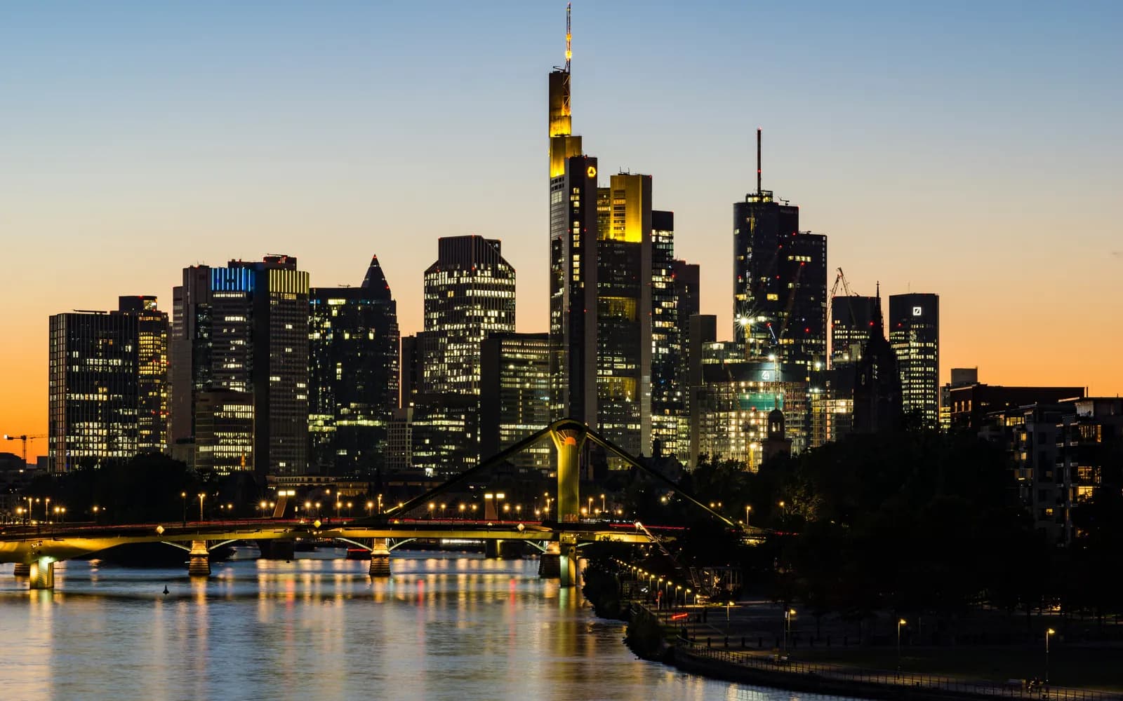 The Frankfurt skyline at dusk, its towers lit above the Main